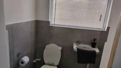 a bathroom with a toilet and a sink and a window at Kenwyn Micro Apartments 2 in Cape Town