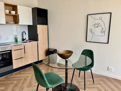 a kitchen with a glass table and two green chairs at Modern Luxe On Park in Cape Town