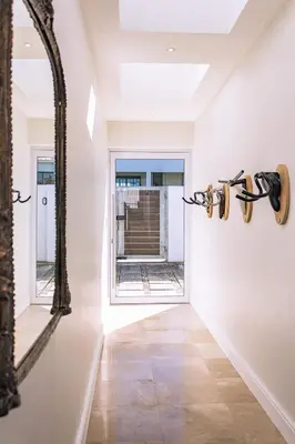 a hallway with a mirror on the wall and a window at Mimosa Voelklip Retreat in Hermanus
