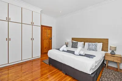 a bedroom with a large bed and white cabinets at Spacious Claremont Home with Pool Fireplace in Cape Town
