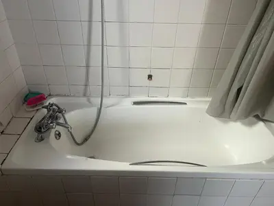 a white bath tub with a hose in a bathroom at home away in Bellville South
