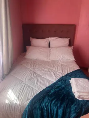 a bedroom with a white bed with a red wall at home away in Bellville South