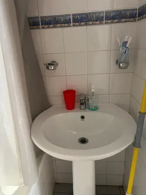 a white bathroom sink with a red cup on it at home away in Bellville South