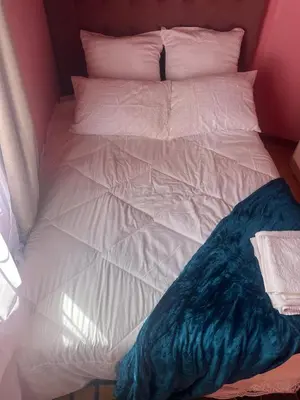 an unmade bed with white sheets and blue blanket at home away in Bellville South