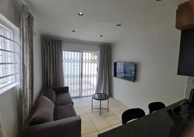 a living room with a couch and a table at Oasis - Renovated - Queen extra length bed apartment in Cape Town