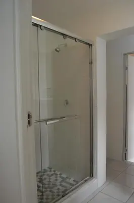 a shower with a glass door in a bathroom at Oasis - Renovated - Queen extra length bed apartment in Cape Town