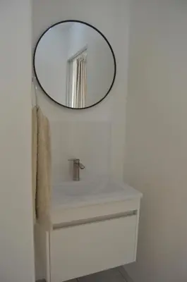 a bathroom with a sink and a mirror on the wall at Oasis - Renovated - Queen extra length bed apartment in Cape Town