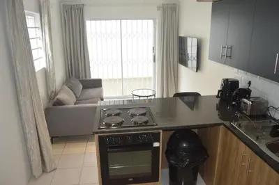 a kitchen with a stove top oven next to a couch at Oasis - Renovated - Queen extra length bed apartment in Cape Town