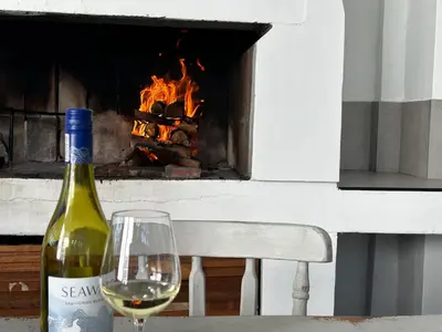 a bottle of wine and a glass on a table at BEACHees - cute central cottage in Kleinmond