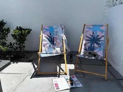 two folding chairs sitting next to a wall at BEACHees - cute central cottage in Kleinmond