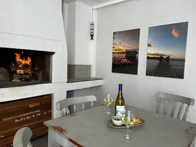 a table with two glasses of wine and a fireplace at BEACHees - cute central cottage in Kleinmond