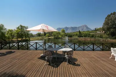 a table and chairs with an umbrella on a deck at Le Pommier Wine Estate in Stellenbosch