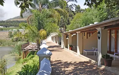 a house with a walkway next to a river at Le Pommier Wine Estate in Stellenbosch