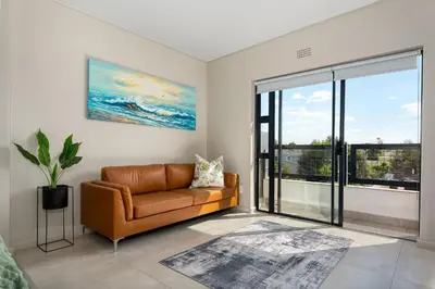 a living room with a couch and a large window at Breeze of the Sea Apartment in Cape Town