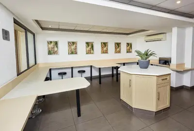 an empty waiting room with tables and stools at SUN1 Parow Cape Town in Avondale