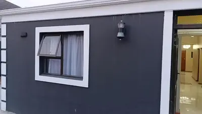 a black building with a window and a light at Spring forth guest house in De Grendel