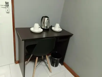 a black table with a tea kettle and a chair at Spring forth guest house in De Grendel
