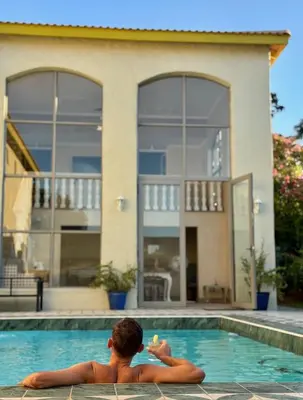 a man sitting in a swimming pool in front of a house at Grande Casa - Central Stellenbosch in Stellenbosch