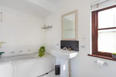 a white bathroom with a sink and a tub and a mirror at Winelands Golf Lodges 1 in Onder-Papegaaiberg