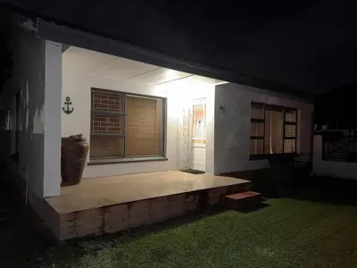 a small house with a window and a bench in the yard at Barking Beach Cottage, Sandbaai - Pet Friendly in Hermanus