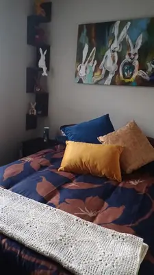 a bedroom with a bed with a blanket and pillows at Sozo - our place at the ocean in Gordonʼs Bay