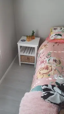 a bedroom with a bed and a white night stand at Sozo - our place at the ocean in Gordonʼs Bay