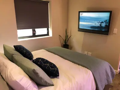 a bedroom with a bed with pillows and a flat screen tv at Modern, Comfy Guest Suite with Beautiful Views in Welgemoed in Tygerberg Hills
