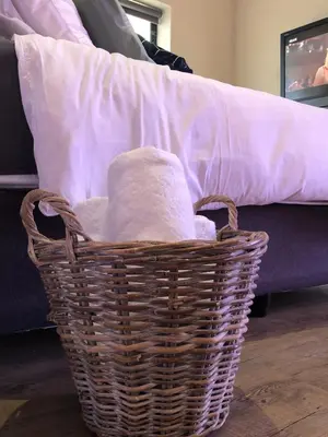 a basket with towels in front of a couch at Modern, Comfy Guest Suite with Beautiful Views in Welgemoed in Tygerberg Hills