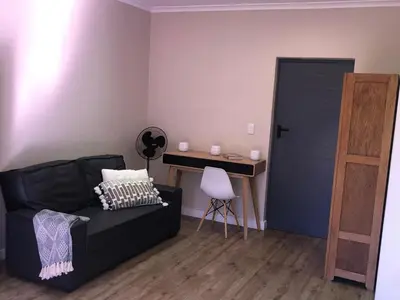 a living room with a black couch and a desk at Modern, Comfy Guest Suite with Beautiful Views in Welgemoed in Tygerberg Hills