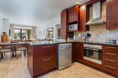 a kitchen with wooden cabinets and a dining room at Holly Tree Franschhoek Accommodation in Franschhoek
