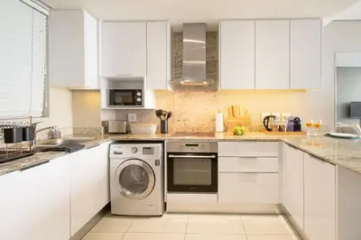 a kitchen with white cabinets and a dishwasher at Stay at Andringa Walk Luxury Apartment in Stellenbosch