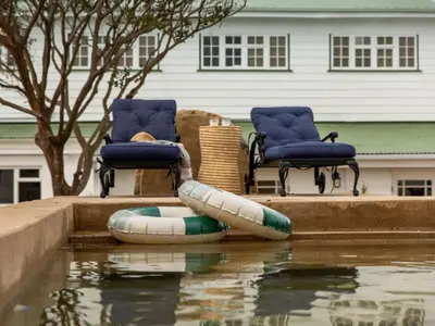 a pool of water with two chairs and an inflatable raft at Little Villa by Ideas Cartel in Hermanus