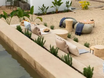 a table with pillows and chairs next to a body of water at Little Villa by Ideas Cartel in Hermanus