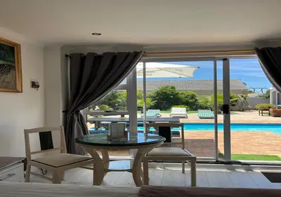 a living room with a table and chairs and a pool at Modern Studio with Pool, 5 mins from Beach in Cape Town