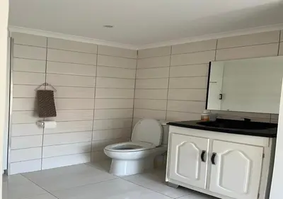 a bathroom with a white toilet and a mirror at Modern Studio with Pool, 5 mins from Beach in Cape Town