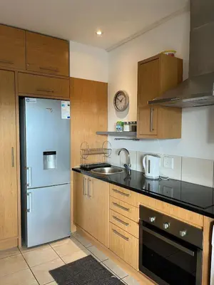 a kitchen with a stainless steel refrigerator and wooden cabinets at Century City Studio with Table Mountain Views in Cape Town