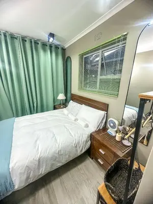 a bedroom with a white bed and green curtains at 29Windsor in Silver Sands