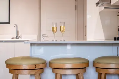 two glasses of wine sitting on a bar in a kitchen at Oceanfront Escape with mountain views in Hermanus