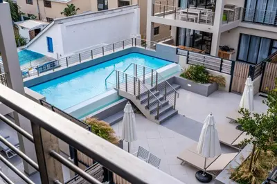 an overhead view of a swimming pool on a building with umbrellas at Oceanfront Escape with mountain views in Hermanus