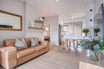 a living room with a couch and a kitchen at Oceanfront Escape with mountain views in Hermanus