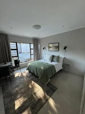 a bedroom with a bed and a desk and a window at The Peaceful Nook Somerset 2 in Somerset West