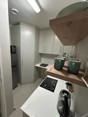 a kitchen with white cabinets and green bowls on a counter at The Peaceful Nook Somerset 2 in Somerset West