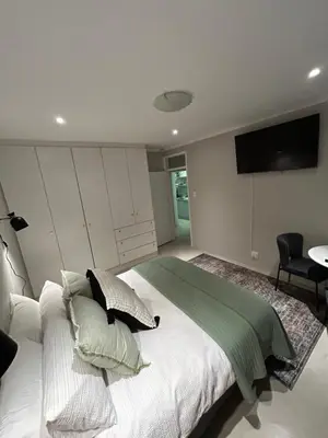 a bedroom with a large bed with a television on the wall at The Peaceful Nook Somerset 2 in Somerset West