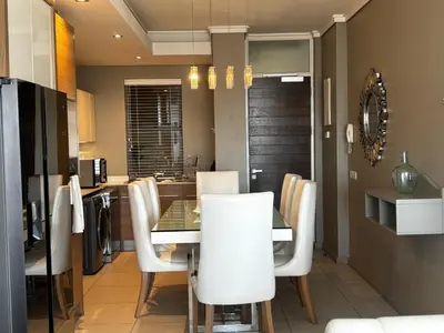 a dining room with a table and white chairs at Luxury Penthouse -Crystal Towers in Cape Town