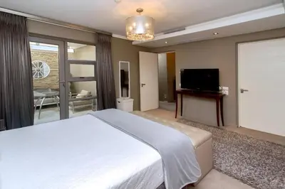 a bedroom with a large bed and a flat screen tv at Luxury Penthouse -Crystal Towers in Cape Town