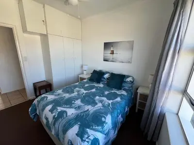 a bedroom with a blue and white bed and a window at Greenways Getaway in Gordonʼs Bay