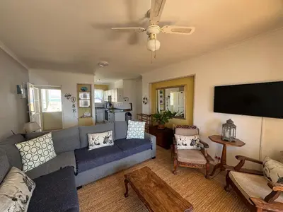 a living room with a blue couch and a flat screen tv at Greenways Getaway in Gordonʼs Bay