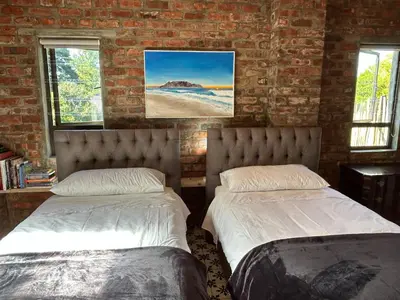 two beds in a room with a brick wall at Garden Studio in Greyton