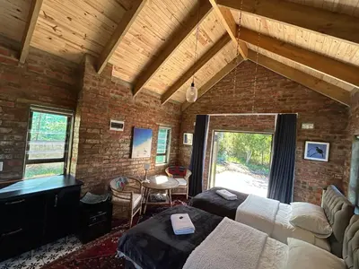 a bedroom with two beds and a piano in a brick wall at Garden Studio in Greyton