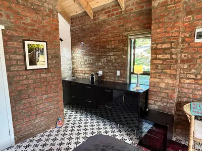 a room with a brick wall and a black desk at Garden Studio in Greyton